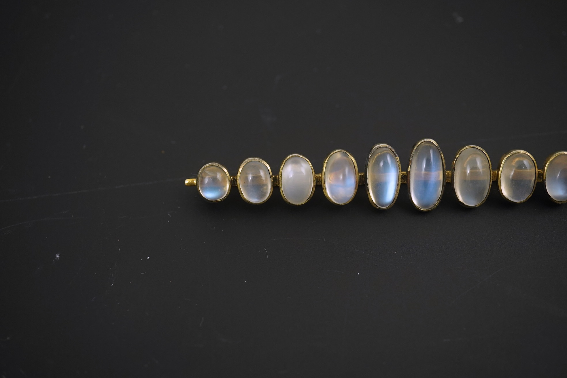 A gold and eleven stone graduated cabochon moonstone set bar brooch